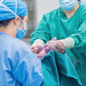 Medical professionals holding a newborn baby in a hospital setting, highlighting care.