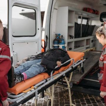 Paramedics loading a patient onto an ambulance stretcher for emergency transportation.